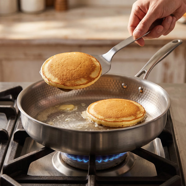 A hand tilting the pan while a spatula lifts an egg with crisp edges